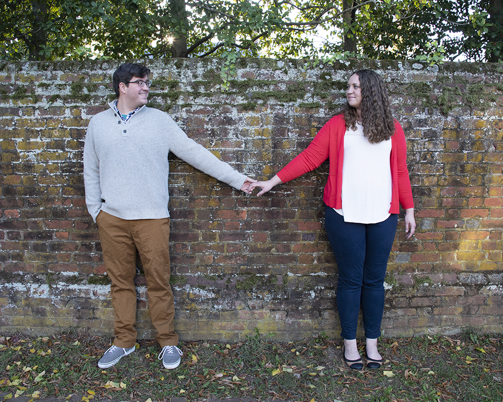 Newly engaged couple posing for a picture holding hands