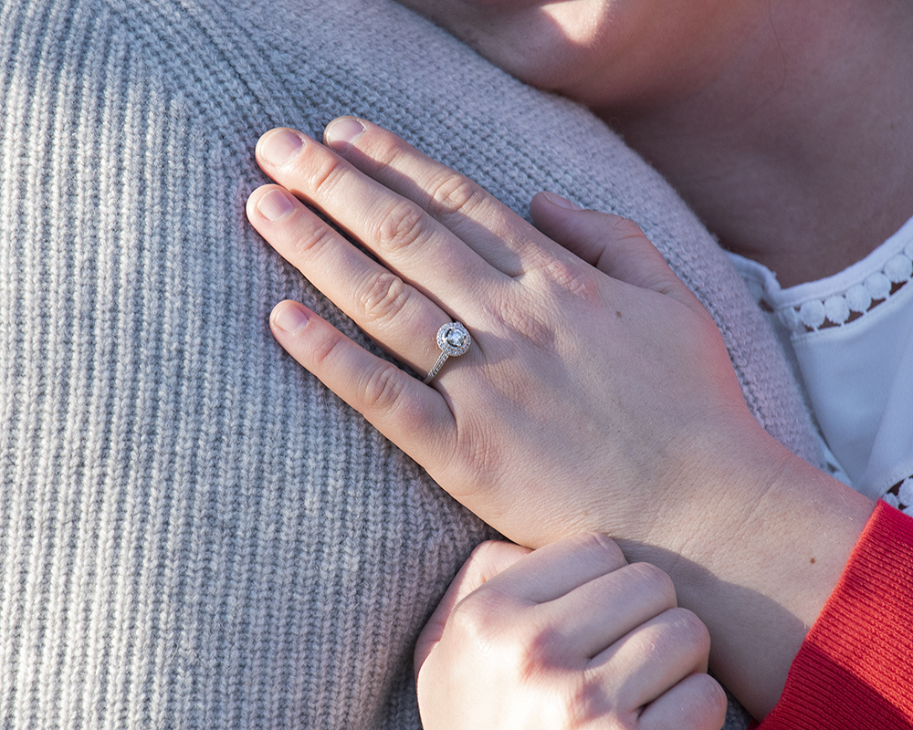 Newly engaged couple posing for a picture showing off engagement ring