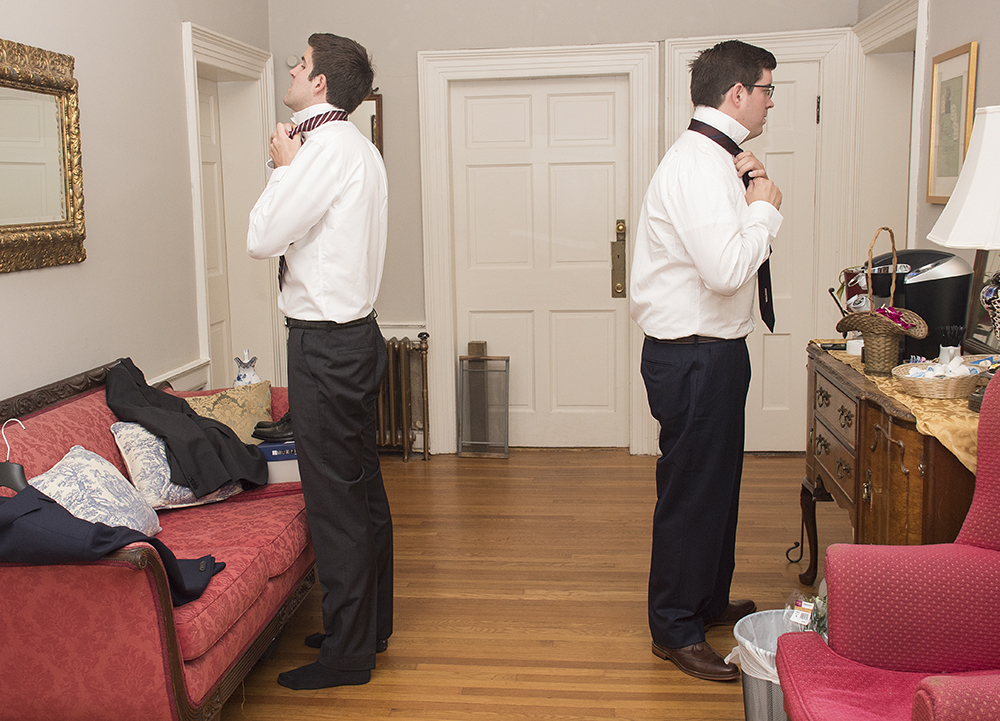Groom and best man getting ready for wedding by putting on ties