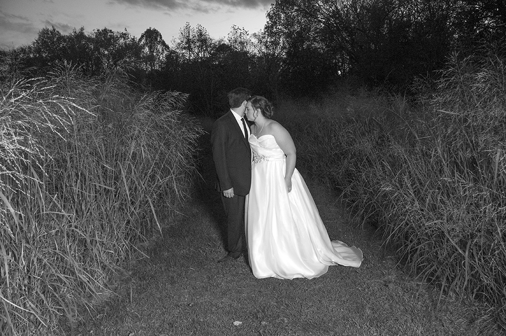 Newly wedded couple posing for a picture in a field