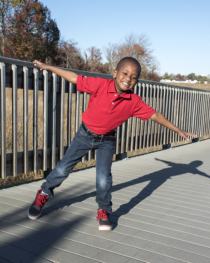 Young boy posing for a picture balancing on one foot and hands out