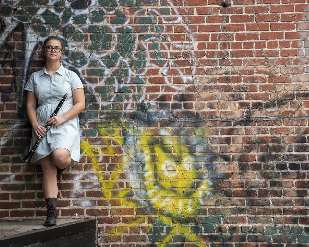 Young female posing for senior picture on location with clarinet in hand