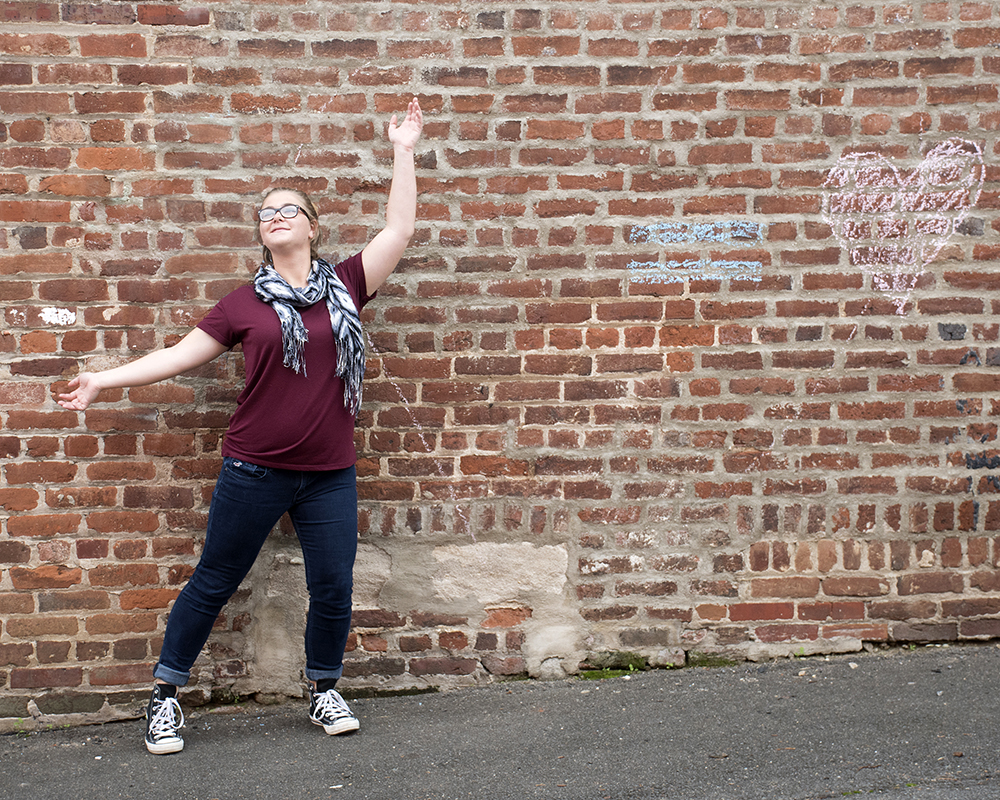Young female posing for senior picture on location with arms in the air