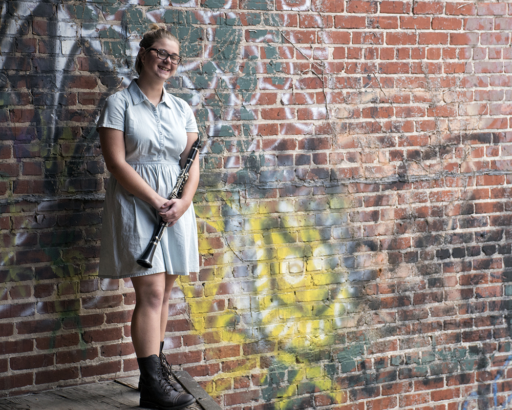 Young female posing for senior picture on location with clarinet in hand