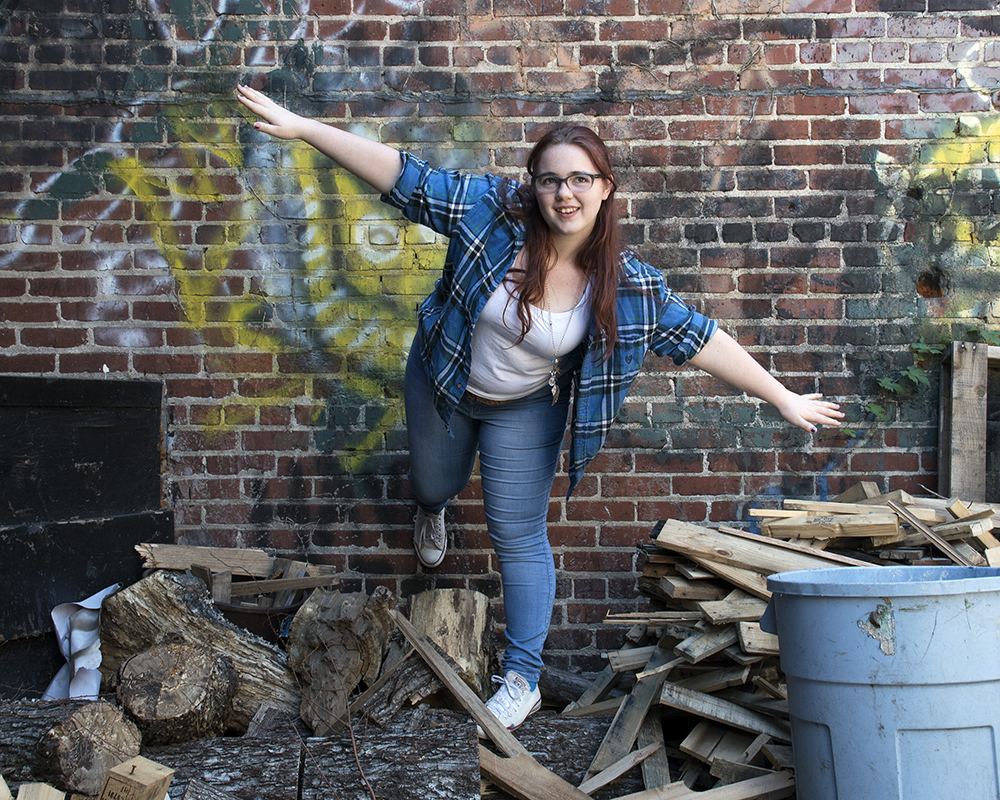 Young female posing for senior picture on location on one foot