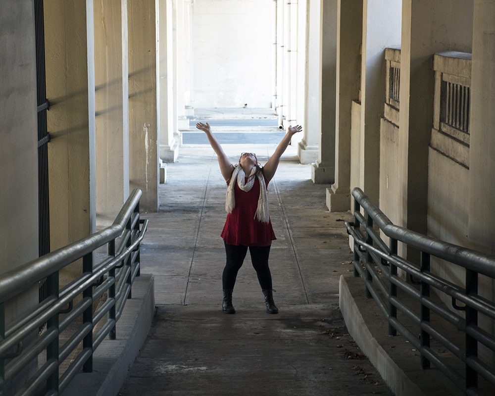 Young female posing for senior picture on location with hands in the air