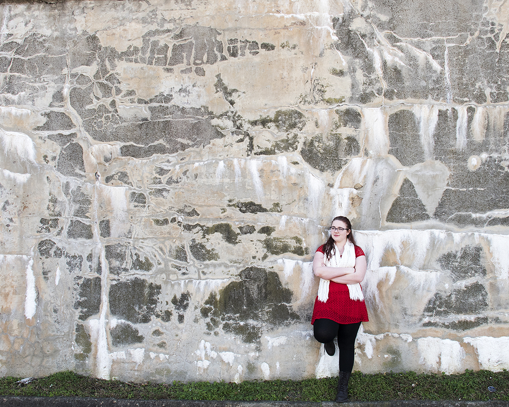 Young female posing for senior picture on location against rock wall