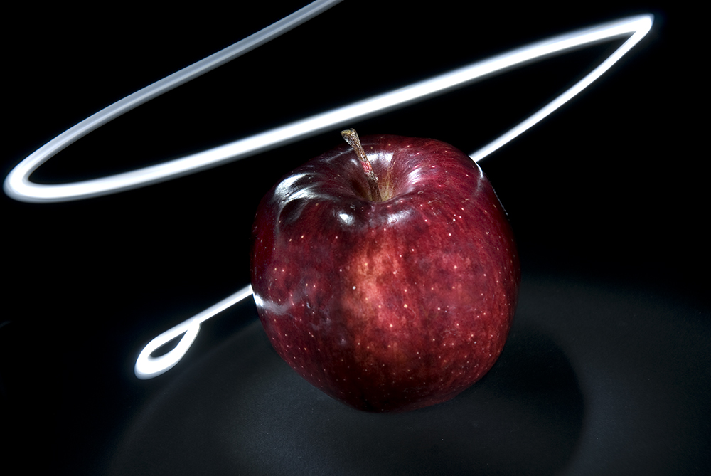 An apple being lite by a pinpoint flashlight
