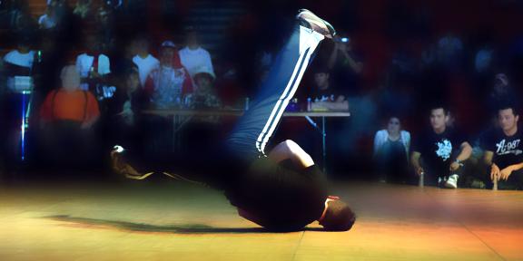 An RIT male student performing a windmill breakdance move in competition